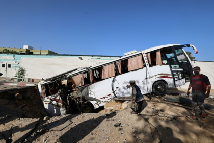 An Israeli air strike in the south Gaza city of Khan Yunis leaves a crater that pulls in a bus. - Eyad BABA (AFP)
