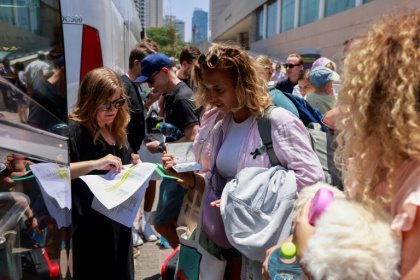 People register before the departure of a bus slated to evacuate foreign passport holders, mainly European, out of Israel, at a meeting point in Tel Aviv - Menahem KAHANA (AFP)
