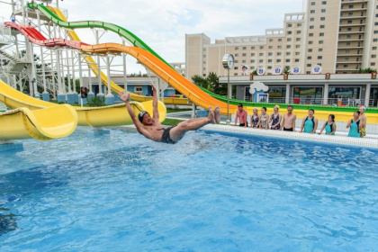 Domestic tourists watch as a man uses a slide into a swimming pool at the Myongsasimni Water Park in North Korea - KIM Won Jin (AFP)
