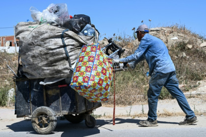 It's common to see people in Tunis weighed down by bags of plastic bottles along the roadside - FETHI BELAID (AFP)