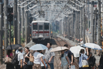 Heat haze is seen in the background as pedestrians with umbrellas cross a railroad on a hot August 5 in Tokyo - Kazuhiro NOGI (AFP)