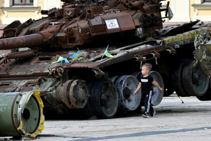 A boy walks past a destroyed tank at an open air exhibition of destroyed Russian military equipment in Kyiv on August 13, 2025, amid the Russian invasion of Ukraine - Sergei SUPINSKY (AFP)
