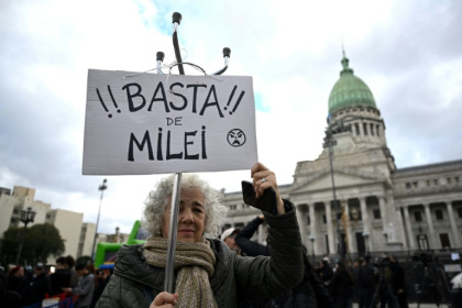 A woman holds a sign that reads in "Enough of Milei," outside of National Congress in Buenos Aires - Luis ROBAYO (AFP)