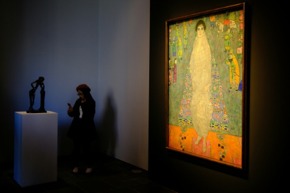 The piece represents the daughter of Klimt's main patron dressed in a white imperial Chinese dress, standing before a blue tapestry with Asian-inspired motifs - CHARLY TRIBALLEAU (AFP)