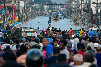 Army personnel ride a truck carrying boats to rescue stranded people as they wade through a flooded road after heavy rainfall on the outskirts of Colombo - Ishara S. KODIKARA (AFP)