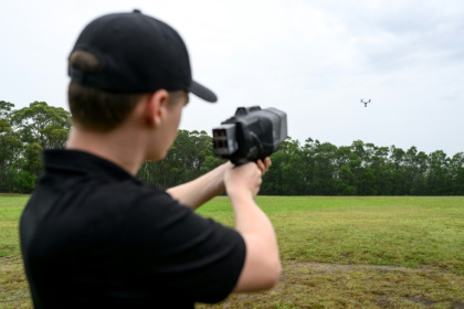A DroneShield team member is holding a DroneGun Mk4 pointed at a drone during a visit to DroneShield in Sydney on February 9, 2026 - STEVEN MARKHAM (AFP)