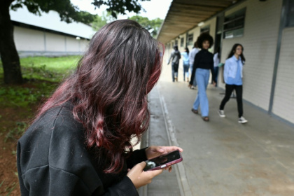 A young student uses her mobile phone at a public school in Planaltina, Brasilia - Evaristo Sa (AFP)