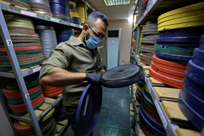 Producer Haider Ibrahim inspects a film reel at the National Centre for Archives and Iraqi Memory in Baghdad - AHMAD AL-RUBAYE (AFP)