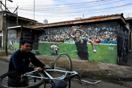 A man is seen next to a mural depicting late Argentine football legend Diego Maradona during the 1986 Mexico World Cup match against England, in Villa Fiorito, on the outskirts of Buenos Aires - Luis ROBAYO (AFP)